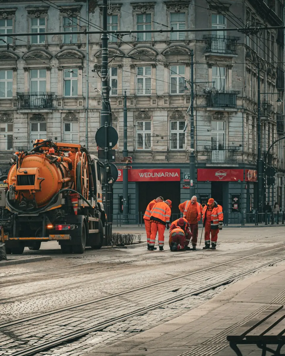 Squadra di spurgo con l’autospurgo arancione al lavoro su una strada